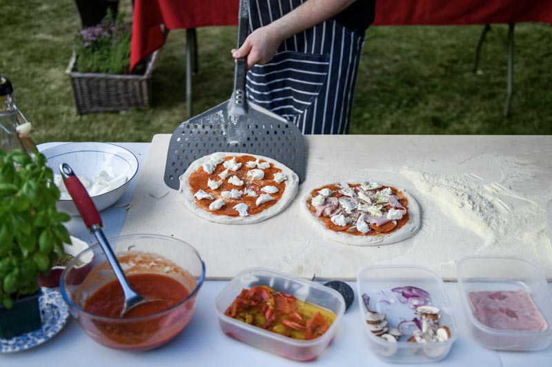 Pizza preparation area with ingrediaents and two ready to cook Neapolitan style pizze