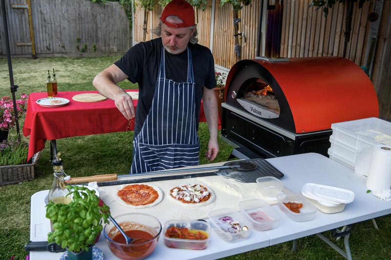 Pizzaiolo Paolo in action making original italian style pizza in a garden 